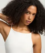 Blusa femenina sin mangas, confeccionada en tejido de algodón con elastano. Presenta un diseño ajustado al cuerpo con escote halter y tirantes finos elásticos.