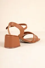 Sandalias de cuero sintético color marrón, con tiras cruzadas y hebilla metálica ajustable. Cuentan con un taco ancho de 6cm de alto.