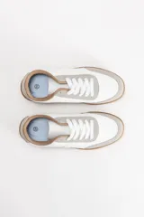 Zapatilla acordonada de diseño minimalista, con cuerpo en color blanco, detalles en gamuza gris claro y suela de goma en tono caramelo.