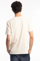 Remera de algodón color beige con estampa frontal gráfica que incluye la frase 'Todo bien' en color verde y un dibujo de una silla de oficina con texto descriptivo debajo.