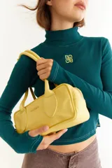 Top de cuello alto y manga larga con diseño ajustado. Presenta costuras a contratono, aberturas laterales en el ruedo y detalle de dedal en los puños. Incluye un bordado distintivo en el centro del pecho.