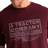 Remera color borgoña con estampa frontal gris de una máquina y texto "A Tractor Company Peoria USA".