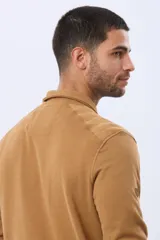 Buzo de felpa color verde oscuro, con cuello tipo polo, cierre frontal parcial con botones y bolsillos laterales. Presenta puños y ruedo acanalados.