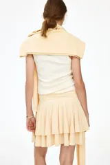Pollera mini escalonada de punto de crepé color beige, con pretina ancha y cinturón para atar lateralmente en forma de lazo.