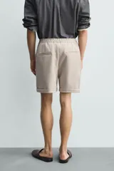 Bermuda regular fit de tejido elástico color blanco, con cintura elástica ajustable mediante cordón, bolsillos delanteros y bolsillos traseros de vivo.