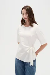 Remera negra de manga corta, con cuello redondo y diseño holgado con detalle de lazo para anudar en la cintura.