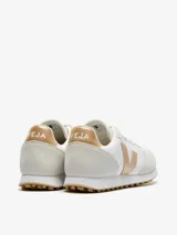 Championes Veja modelo SDU, confeccionados en Alveomesh blanco con paneles de gamuza vegana y detalles en color platino. Presentan el logo de la marca en el lateral, cierre con cordones y suela de caucho.