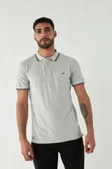 Remera polo negra de manga corta con ajuste regular. Presenta cuello y puños con ribete a rayas en gris y bordó. El logo de la marca está estampado en el pecho.
