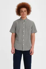 Camisa de manga corta con cuello clásico y cierre frontal de botones. Presenta un patrón de cuadros tipo gingham en color negro y blanco, con un bolsillo en el pecho que incluye la etiqueta roja característica de la marca.