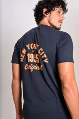Remera de cuello redondo y manga corta en color azul marino, con estampado pequeño en el pecho que incluye el texto New York City 1955 Original en color naranja.