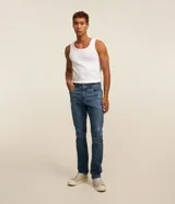 Pantalón skinny de jean nevado para hombre, confeccionado en denim de algodón con elastano. Presenta un lavado azul medio con ligeros desgastes y calce ajustado.