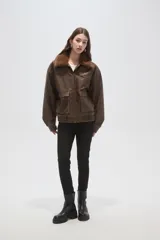 Campera de eco-cuero color marrón con cuello de piel sintética, cierre frontal, bolsillos frontales con solapa y puños y cintura elásticos.