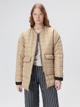 Campera reversible capitoneada con cierre frontal. Un lado es de color negro y el otro es de color beige, ambos con diseño acolchado. Cuenta con cuello redondo, mangas largas y bolsillos laterales.