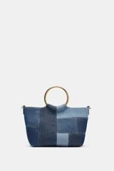 Bolso de hombro tipo mini saca con cuerpo en patchwork de denim en tonos azules. Posee una anilla metálica dorada como asa de mano y una correa bandolera extraíble.