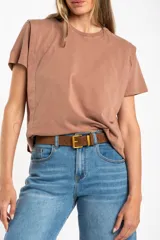 Remera de algodón color mostaza/naranja quemado, con cuello redondo y mangas cortas. Presenta un diseño con costuras externas visibles en los hombros y laterales, dándole un aspecto desestructurado.