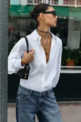 Camisa de algodón con diseño de rayas verticales sutiles, cuello solapa, manga larga con puños abotonados y cierre frontal con botones.