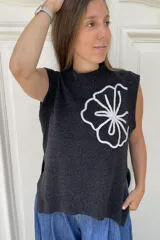 Chaleco de lana color gris oscuro, con diseño sin mangas, cuello redondo y tajos laterales. Presenta un bordado artesanal de una flor grande en color blanco en el frente.