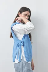 Chaleco tejido de punto con silueta relajada y diseño sin mangas. Presenta lazos laterales ajustables y cuello redondo.