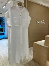 Vestido camisero largo de lino color blanco, con cuello mao, mangas cortas, bolsillos delanteros y botones de nácar. Presenta aberturas laterales en el ruedo.