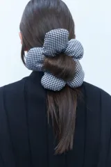 Gomita de pelo con forma de flor, confeccionada en tela con estampado vichy blanco y negro.