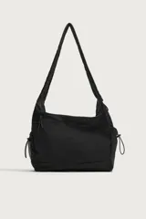 Bolso de hombro negro de nylon, con compartimento principal y bolsillos con cierre de cremallera, bolsillos laterales con cordón ajustable y asa fruncida.