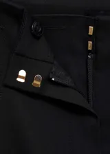Pantalón de tiro medio y corte recto con diseño crop. Presenta detalles de botones dorados estilo joya en la parte frontal y cierre oculto con cremallera y gancho.