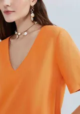 Blusa naranja de lino con escote en V y mangas cortas.