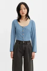 Corset de denim color celeste, con escote cuadrado, mangas largas y cierre frontal con botones metálicos. Presenta costuras verticales que definen la silueta.