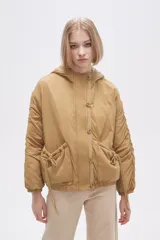 Campera color beige de manga larga con capucha, cierre con botones a presión y bolsillos con cordón ajustable.
