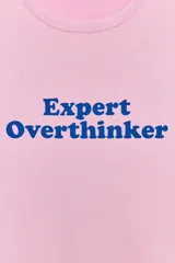 Remera rosa de manga corta y cuello redondo, con el texto "Expert Overthinker" estampado en azul en el centro del pecho.
