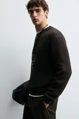 Sweater de punto en canalé color negro, de corte regular fit, cuello redondo y manga larga con terminaciones en rib.