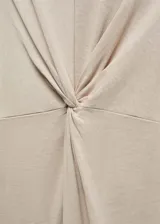 Vestido midi de algodón, color beige, con cuello redondo, sin mangas y detalle de nudo frontal que genera un ligero drapeado.