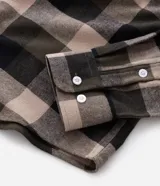 Camisa de franela para hombre, modelo comfort, con estampado de cuadros en tonos azules, blancos y negros, cuello camisero, manga larga y cierre frontal de botones.