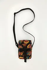 Mini bolso bandolera de poliéster color negro con estampado colorido de bananas. Cuenta con correa ajustable, solapa con cierre de hebilla plástica y detalles en red.
