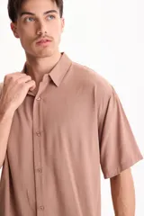 Camisa de viscosa negra de manga corta, con cuello camisero y cierre frontal de botones, de corte oversize.