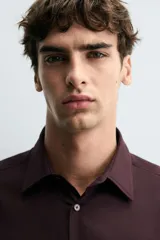 Camisa blanca de manga larga con cuello italiano y cierre frontal de botonadura. Corte regular fit.