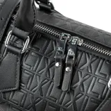 Cartera tipo baúl color negro, confeccionada en símil cuero con diseño de logotipo en relieve. Cuenta con doble cierre superior, asas cortas de mano y correa larga regulable y extraíble. Incluye herrajes plateados.