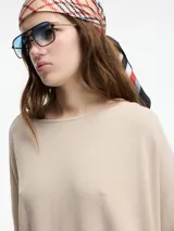 Sweater beige de mangas 3/4, con fit amplio y largo más pronunciado en la parte trasera.