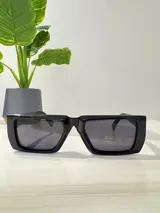 Lentes de sol rectangulares con montura gruesa de acetato color negro y cristales grises.