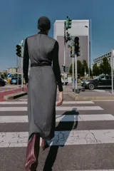 Vestido midi jaspeado en tonos grises, con cuello redondo, manga sisa y bajo en evasé. Incluye un cinturón ancho negro con hebilla rectangular y cierre de cremallera oculta en la espalda.