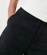 Bermuda negra de poliamida con textura capitoneada y bolsillos laterales.