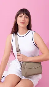 Bandolera color marrón oscuro con textura granulada, dos compartimentos principales con cierre, un bolsillo frontal con solapa y botón, y un bolsillo trasero con cierre. Incluye correa de tela ajustable.