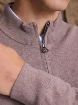 Sweater de punto color azul marino, con cuello alto y cierre frontal parcial, de manga larga y puños acanalados.