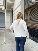 Blusa de manga larga en color crudo, confeccionada en tejido suave y abrigado, con cuello redondo y corte holgado.
