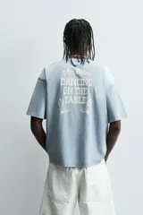 Camiseta de manga corta y cuello redondo, color celeste lavado, con estampado frontal en blanco que dice "The Mr. Rebel Dance".