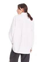 Camisa oversized de algodón color gris claro, con cuello clásico, botones negros y bolsillo frontal con etiqueta de marca.