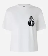 Blusa blanca de algodón con cuello redondo y mangas cortas. Presenta un estampado de una caricatura de una mujer con boina, lentes de sol y un trago en la mano.