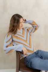 Sweater de punto jacquard con diseño de chevron en tonos celeste y marrón. Presenta cuello redondo, corte holgado y mangas largas con hombros abullonados.