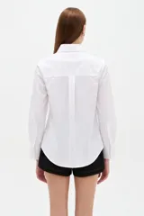 Camisa de algodón blanca, de corte entallado al cuerpo, con cuello camisero, manga larga y cierre frontal de botones.