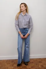 Camisa de mujer a rayas verticales blancas y rosadas, con cuello clásico, cierre de botones frontal y mangas largas con puños abotonados.